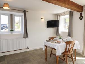 a dining room with a table and two windows at Cuckoo Cottage in Keighley
