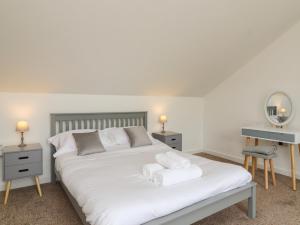 a bedroom with a white bed with two towels on it at Cuckoo Cottage in Keighley