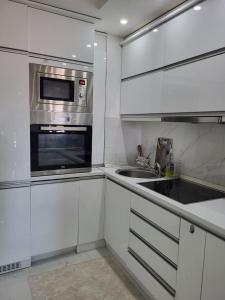 a white kitchen with a microwave and a sink at Chic and Cozy Apartment on the Main Pedestrian Street in Struga