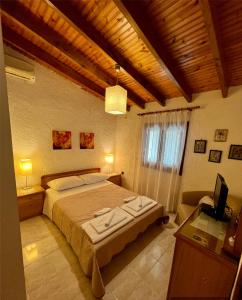 a bedroom with a bed and a desk and a television at DIMIS swimming pool small villa in Eretria