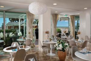 a restaurant with white tables and chairs and windows at Hotel Ca' Bianca in Riccione