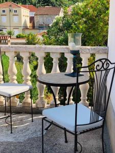 2 sillas, mesa y jarrón en el balcón en Authentic Vila Nona by NYC Interior Architect en Susak