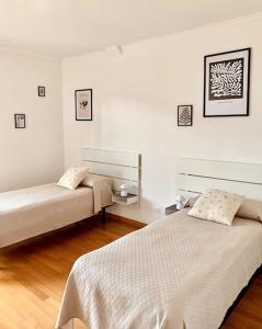 two beds in a room with white walls and wooden floors at La Dolse Ca' - Lago di Garda in Brenzone sul Garda