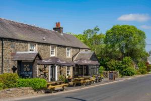 um prédio com bancos e guarda-sóis na frente em Cross Keys Inn Ettrickbridge em Ettrickbridge End