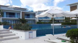a swimming pool with two chairs and an umbrella at Villasun Seafront Apart at CapOuest in Flic-en-Flac