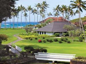 een huis op een golfbaan met palmbomen en de oceaan bij Kiahuna Plantation Resort Kauai by OUTRIGGER in Koloa