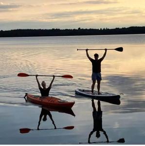 two people standing on a paddle board in the water at Svanen B&B in Karlsborg
