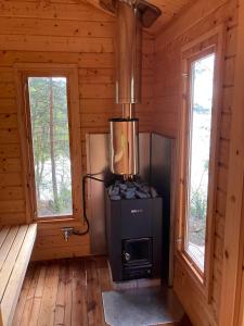 a woodburning stove in a log cabin with two windows at Svanen B&B in Karlsborg