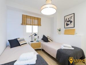 a bedroom with two beds and a light fixture at Living Las Canteras Homes - BEACHFRONT IN STYLE in Las Palmas de Gran Canaria