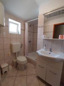La salle de bains est pourvue d'un lavabo, de toilettes et d'une baignoire. dans l'établissement Apartmani Danica, à Vrbnik