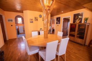 jadalnia z drewnianym stołem i białymi krzesłami w obiekcie Farkas Guesthouse w mieście Balatonszentgyörgy