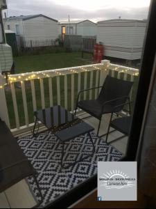 a patio with two chairs and lights on a fence at Skegness - Ingoldmells Caravan Hire in Ingoldmells