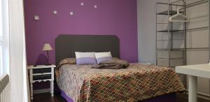 - une chambre avec des murs violets et un lit avec une couverture dans l'établissement Casa de Huéspedes con encanto El Sueño del Quijote, à Alcalá de Henares