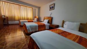 a hotel room with three beds and a window at Hotel Wanka Palace in Huancayo