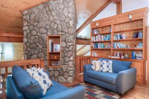 sala de estar con sofá azul y pared de piedra en Havencrest Luxury Home with Long Range Mountain & Lake Lure Views!, en Old Fort