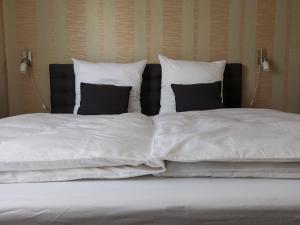 uma cama grande com lençóis brancos e almofadas pretas em Quiet apartment with green view in urban location em Braunschweig