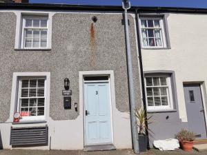 a house with a blue door and two windows at Sandy Shell Cottage in Conwy