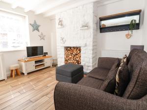 a living room with a couch and a fireplace at Sandy Shell Cottage in Conwy
