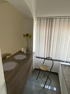 een stoel en een tafel in een kamer met een raam bij Tocc Apartman in Gyál
