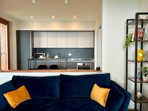 Una sala de estar con un sofá azul y una cocina. en Lakeview Apartment Lago Maggiore, en Gignese