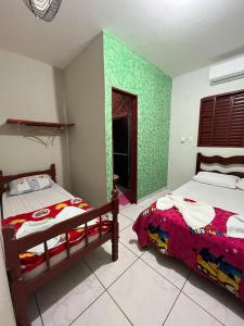 a bedroom with two beds and a green wall at Pousada Vancele in Bonito