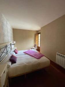 una camera da letto con un grande letto bianco con cuscini viola di Apartamentos Casa Miño a Pola de Somiedo