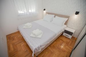 a bedroom with a white bed with two towels on it at Apartman Lena in Trebinje
