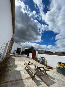 a wooden picnic table on a patio with a cloudy sky at El palacete azul in Almendral