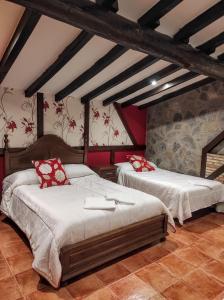 1 dormitorio con 2 camas y almohadas rojas en Apartamentos Rurales Fuente Chiquita, en Hervás