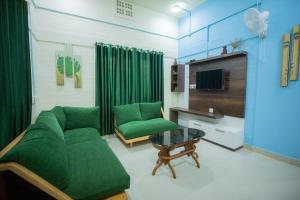 a living room with a green couch and a table at San Unik Homestay in Nilambūr