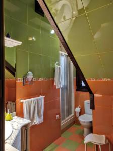 baño con paredes de color naranja y verde y aseo en Apartamentos Rurales Fuente Chiquita, en Hervás