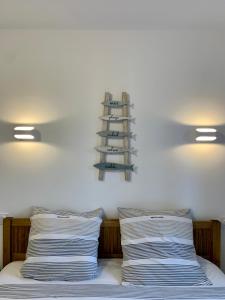 - un lit avec 2 oreillers et une étagère sur le mur dans l'établissement LA BADINE 5p Plage piscine clim jacuzzi parc luxuriant, à Hyères