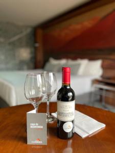 - une bouteille de vin et un verre de vin sur une table dans l'établissement Hotel Cumbres Lastarria, à Santiago