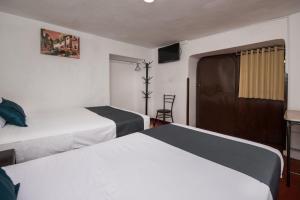 una habitación de hotel con 2 camas y una silla en Ayenda Hostal Cusco Sol, en Cusco