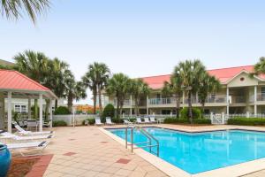 a resort pool with lounge chairs and palm trees at Sugar Sand Oasis in Santa Rosa Beach