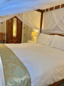 WE ARE UNIQUE ! 4 min walk to Beach, Pubs, Restaurants, Shops, Htd Pool, Hottub, Games rm, 1 acre Garden, BBQ, Stunning walks, Historic Bassets acre, 6 x 1-3 bedroom Superior aparts, Free Parking and WIFI في برتريث: غرفة نوم مع سرير أبيض كبير مع مظلة