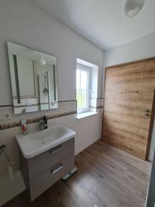 een badkamer met een witte wastafel en een houten deur bij Private Zimmer in Neubau Familienhaus in Alsfeld