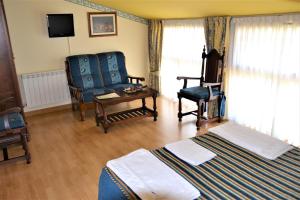 a hotel room with two beds and a chair at Hostal Infanta Doña Leonor in Palencia