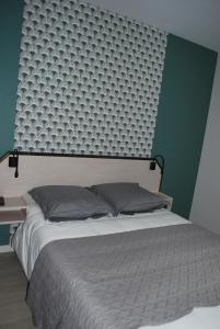 1 dormitorio con cama y pared verde en Hôtel Des Voyageurs, en Bellevue-la-Montagne