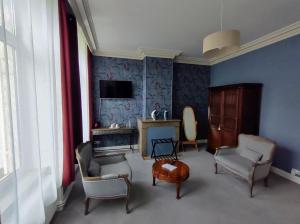 ein Wohnzimmer mit blauen Wänden und Stühlen sowie einem TV in der Unterkunft Maison Grandsire Chambres D'Hôtes in Saint-Léonard