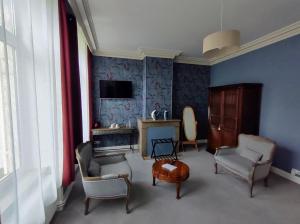 uma sala de estar com paredes e cadeiras azuis e uma televisão em Maison Grandsire Chambres D'Hôtes em Saint-Léonard