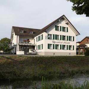 a white building with green windows and a river at Schäfle Landgasthof in Feldkirch