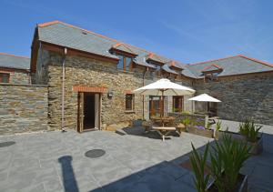 a stone building with an umbrella and a patio at Bowgie in Saint Merryn