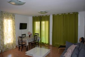 een woonkamer met groene gordijnen en een tafel met stoelen bij Alta Entinas Almerimar .Modern apartment close to beach, beautiful pool. in El Ejido