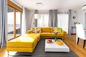 a living room with a yellow couch and a table at Großzügiges Appartement direkt am Meer mit eigenem Pool - Povile Suites in Novi Vinodolski