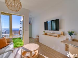 a living room with a couch and a tv at Living Las Canteras Homes - BEACHFRONT IN STYLE in Las Palmas de Gran Canaria