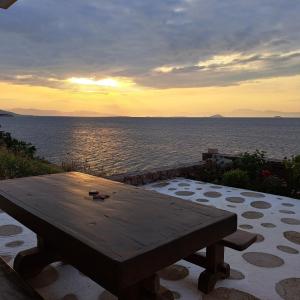 a wooden picnic table sitting on top of the ocean at Ithaca in Perdika