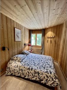 ein Schlafzimmer mit einem Bett in einem Zimmer mit Holzwänden in der Unterkunft Résidences DELAVAY LA FERME in Les Gets