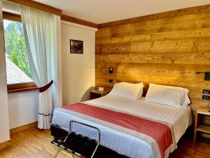 Hotel Croux في كورمايور: غرفة نوم بسرير وجدار خشبي