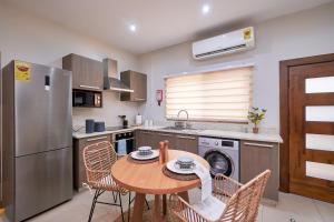 eine Küche mit einem Tisch und Stühlen sowie einem Kühlschrank in der Unterkunft The Avery at Windsor Apartments, Osu in Accra